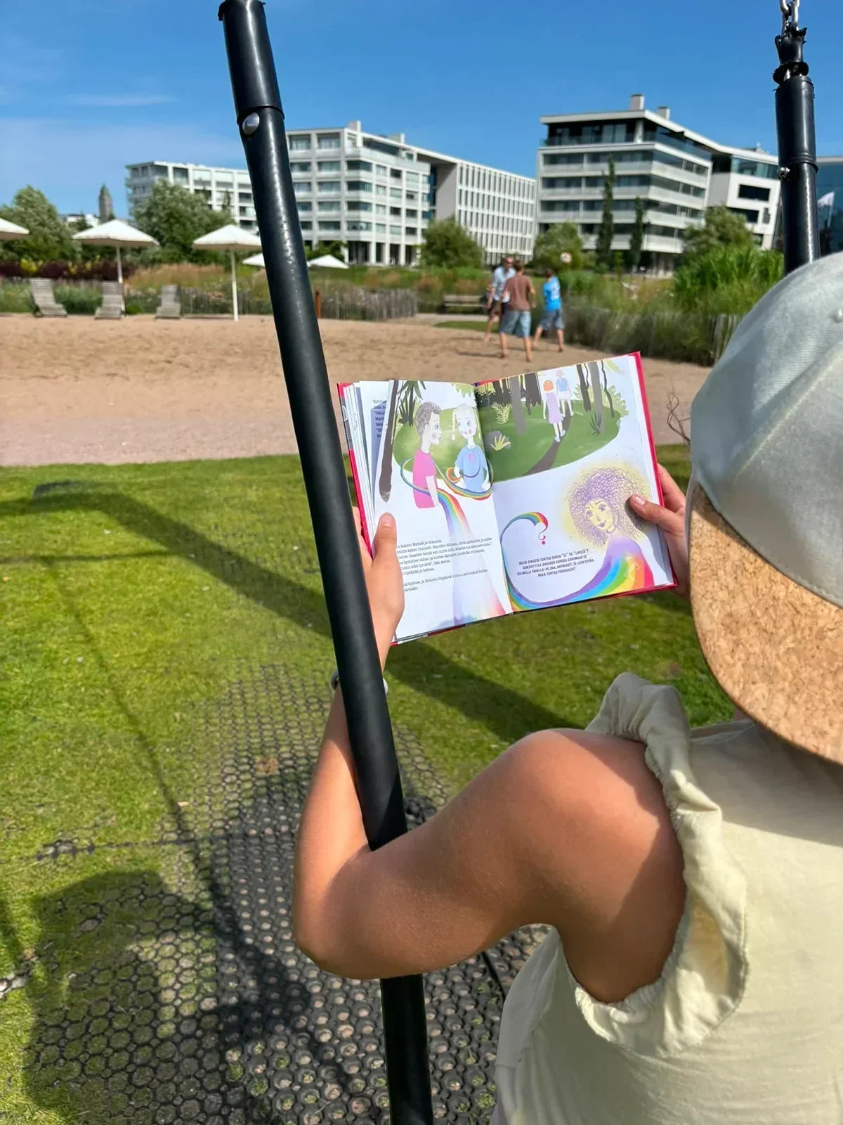 Lapsi lukee keinussa Jenni Hirvensalon kirjoittamaan Ei!-Maailman tärkein pieni sana -turvataitokirjaa.
